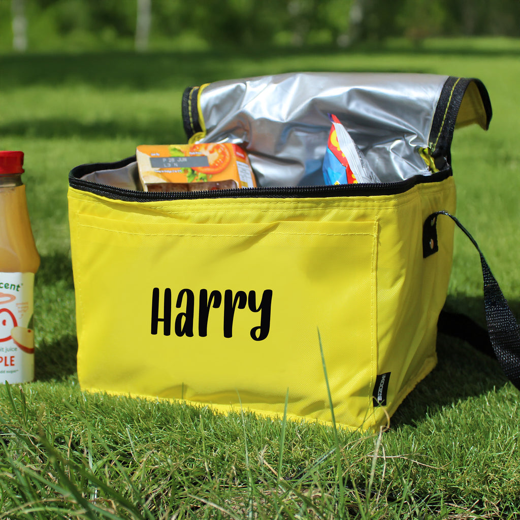 Yellow cooler bag with 'Harry' printed on it, open to reveal food items, on grass.