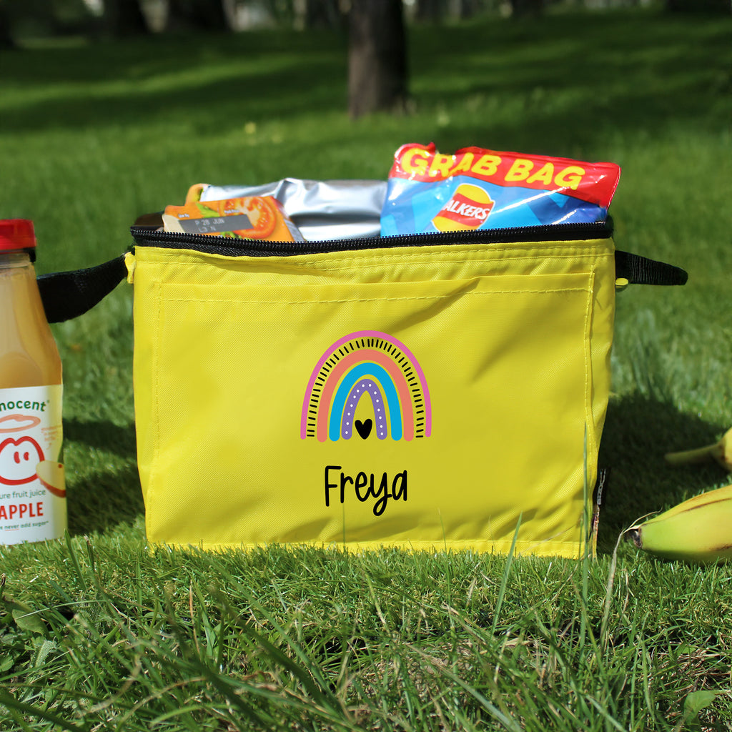 Yellow bag with a rainbow design and 'Freya' text on grass, next to a bottle of Innocent juice.