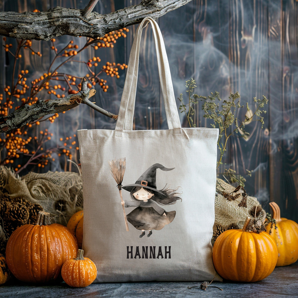 Tote bag with a witch design and 'HANNAH' text, surrounded by pumpkins and Halloween decorations.
