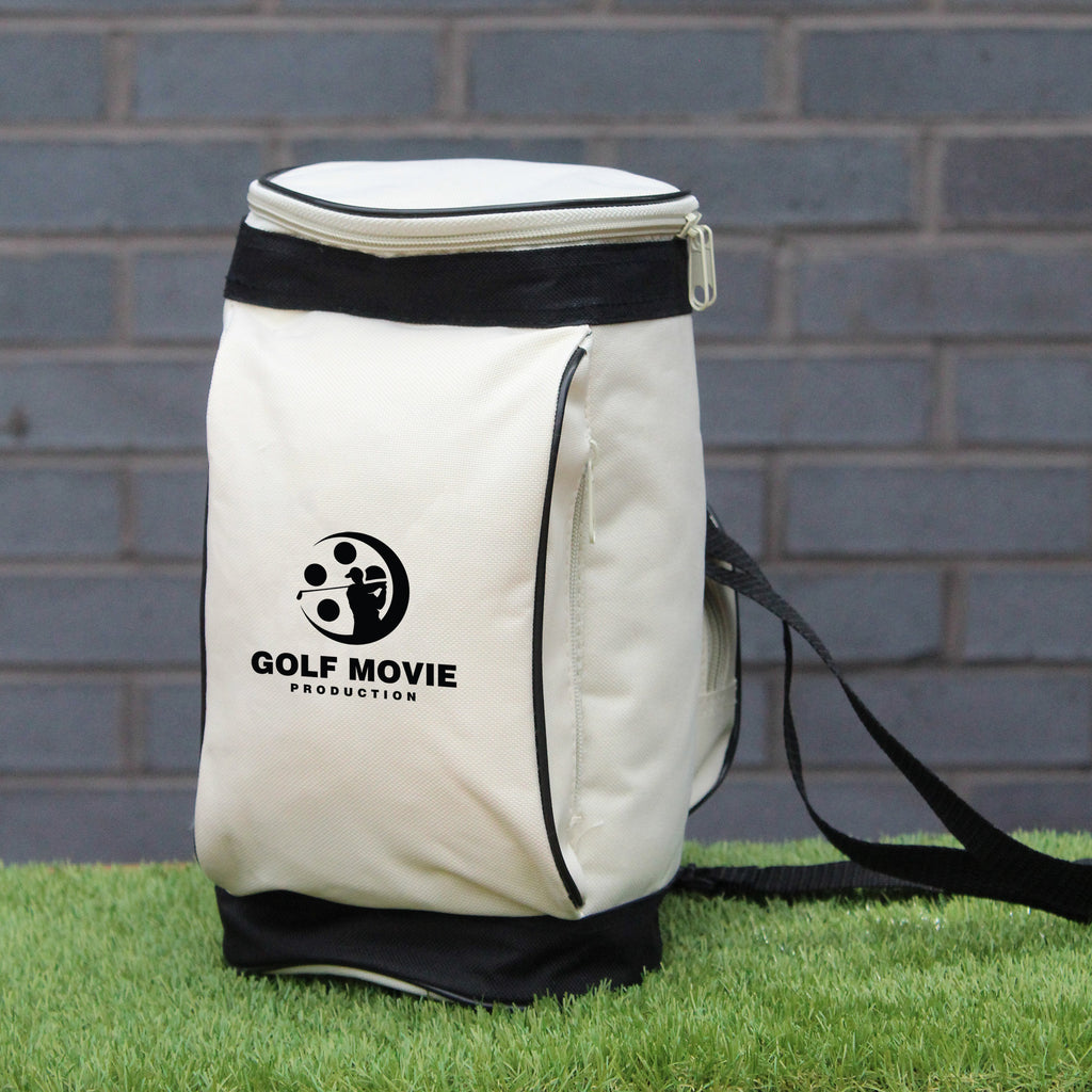 White cooler bag with black trim and 'Golf Movie Production' logo on grass against a brick wall.