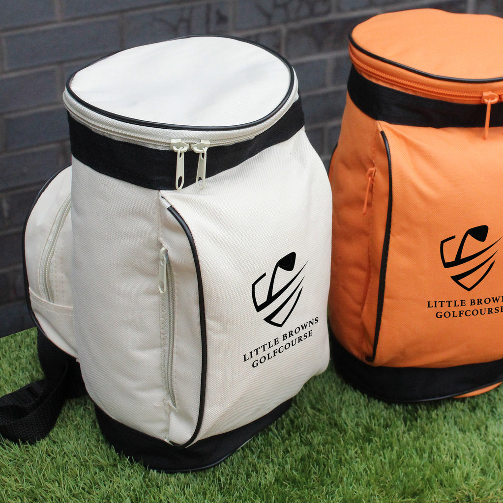 White and orange golf bags with Little Browns Golfcourse logo on grass and brick wall background