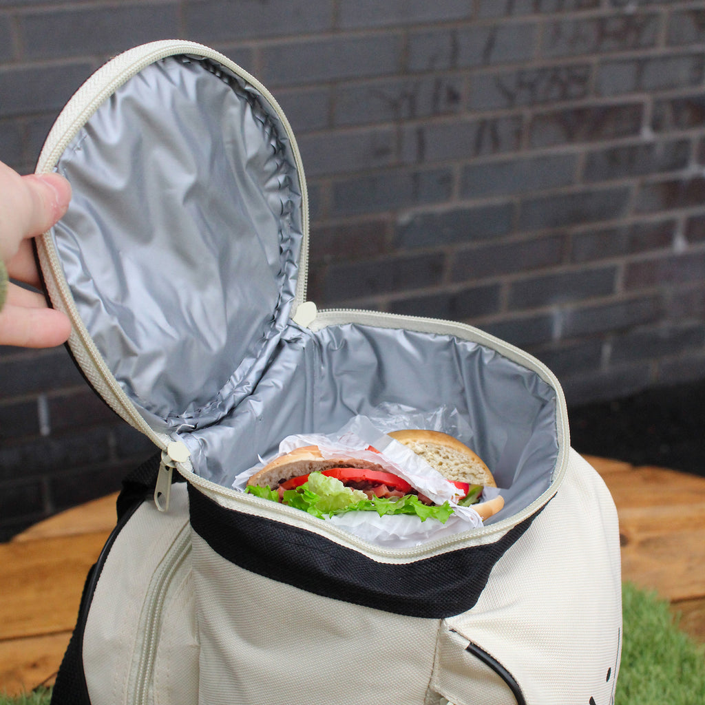 Lunch bag with a sandwich inside, held open against a brick wall.