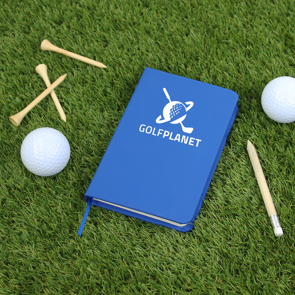 Blue notebook with 'GOLFPLANET' logo on grass with golf balls and tees