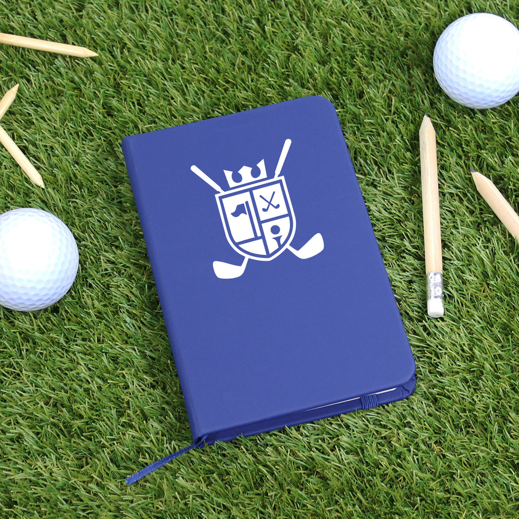 Blue notebook with a white logo on grass with golf balls and clubs