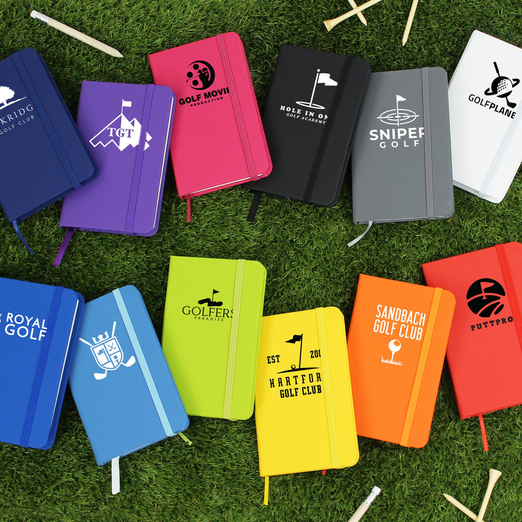 Colorful golf-themed notebooks arranged on a grassy background