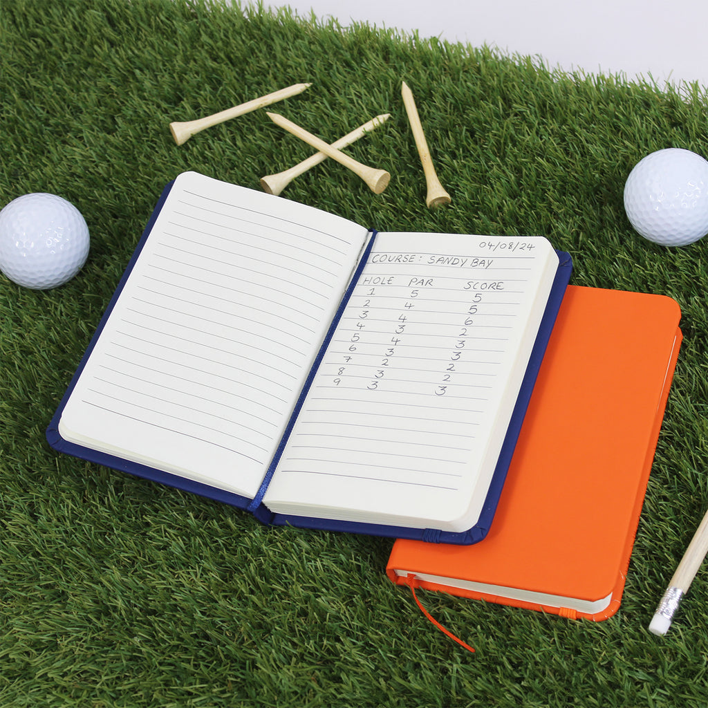 Golf notebook with scorecard on grass with golf balls and tees