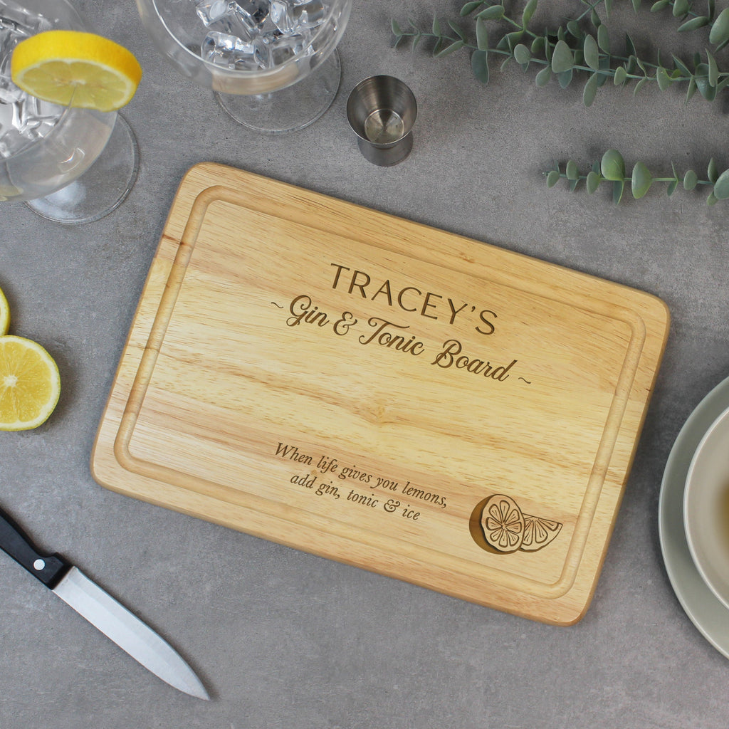 Wooden cutting board with engraved text on a table with drinks and snacks.
