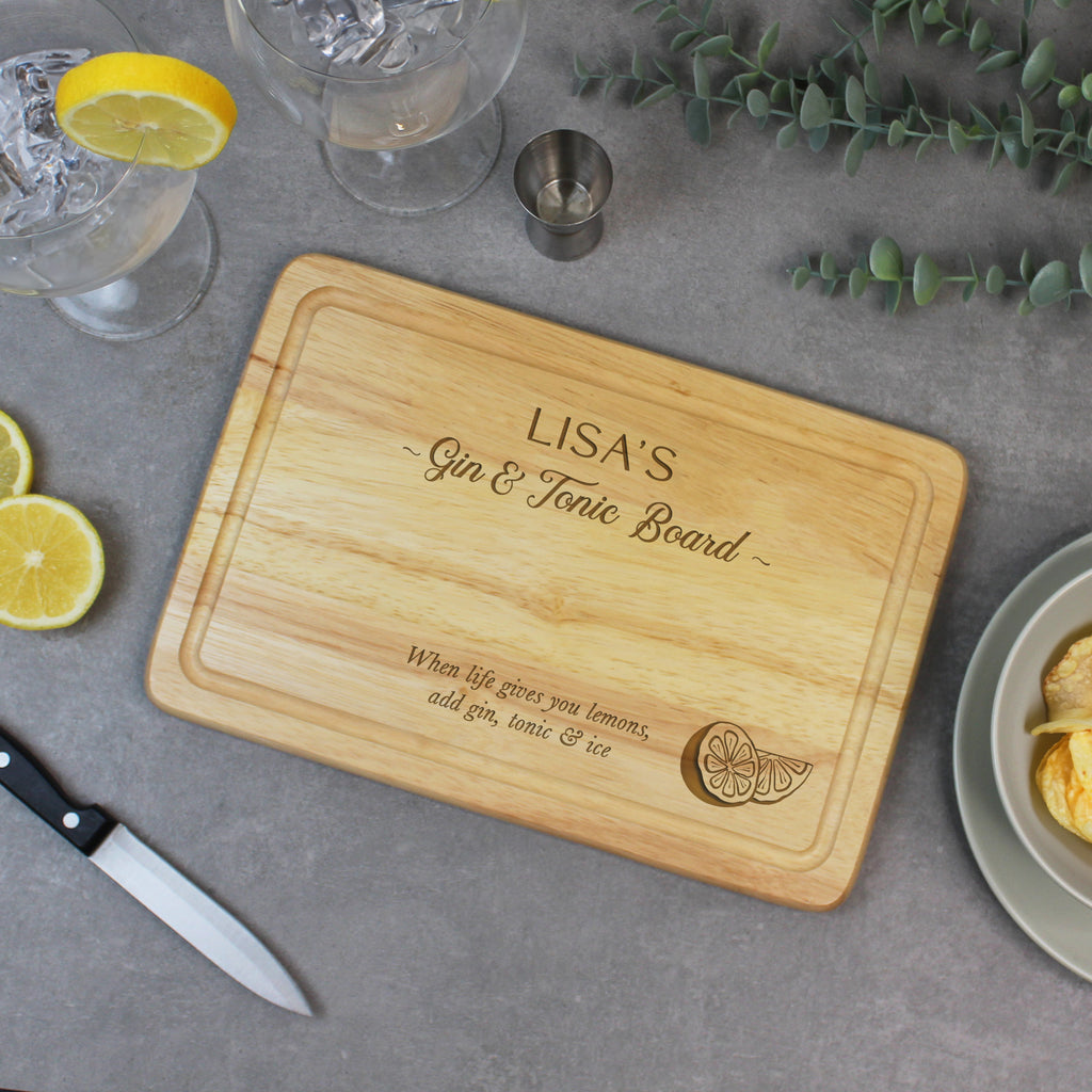 Wooden cutting board with engraved text on a table with drinks and garnishes.