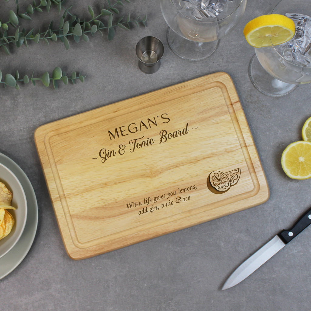 Wooden cutting board with engraved text on a table with lemons and glasses.