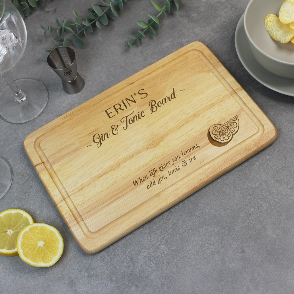 Wooden cutting board with engraved text on a gray surface with lemons and a glass.