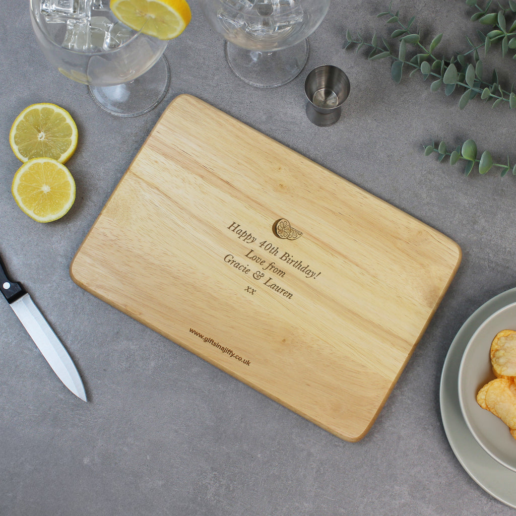 Wooden cutting board with engraved text on a table with lemons, glasses, and a knife.