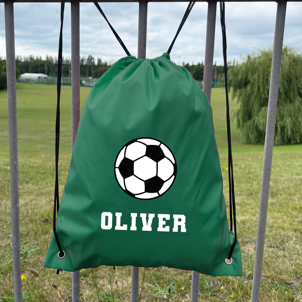 Green drawstring bag with soccer ball design and 'OLIVER' text, placed against a grassy field background.
