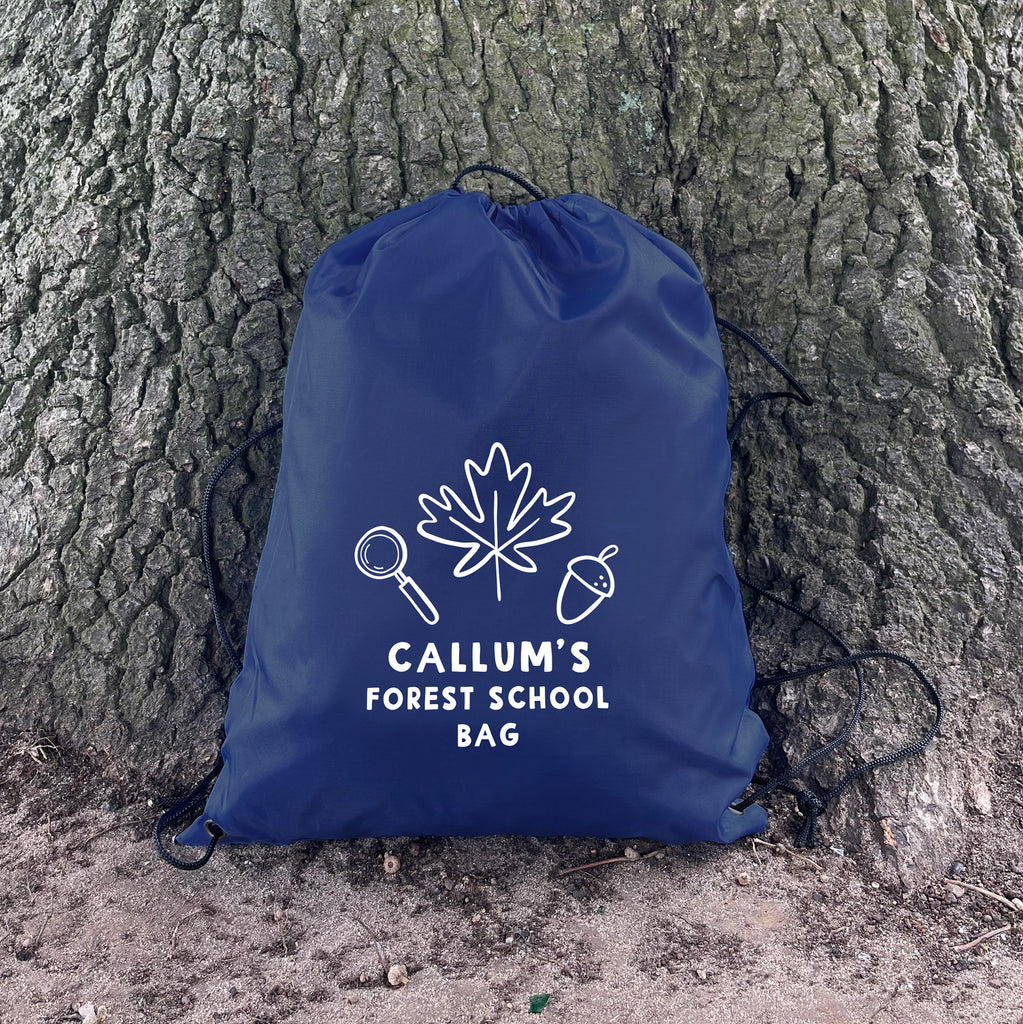 Blue drawstring bag with 'Callum's Forest School Bag' text and nature-themed design against a tree trunk.