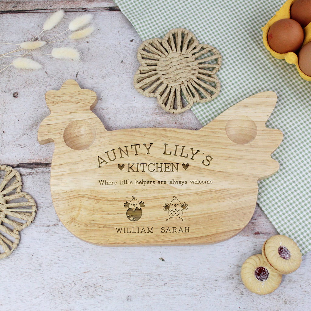 Wooden cutting board shaped like a chicken with engraved text on a rustic wooden surface.