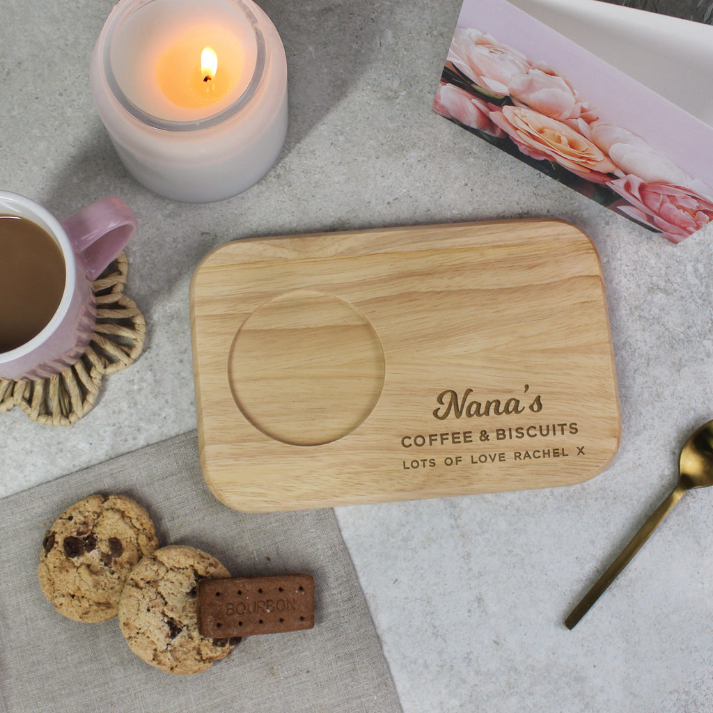 Personalized wooden coaster with 'Nana's Coffee & Biscuits' text, surrounded by a cup of coffee, cookies, and a candle.