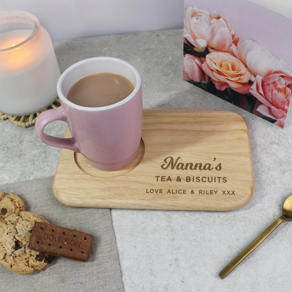 Pink mug with wooden coaster on a table with cookies and a candle