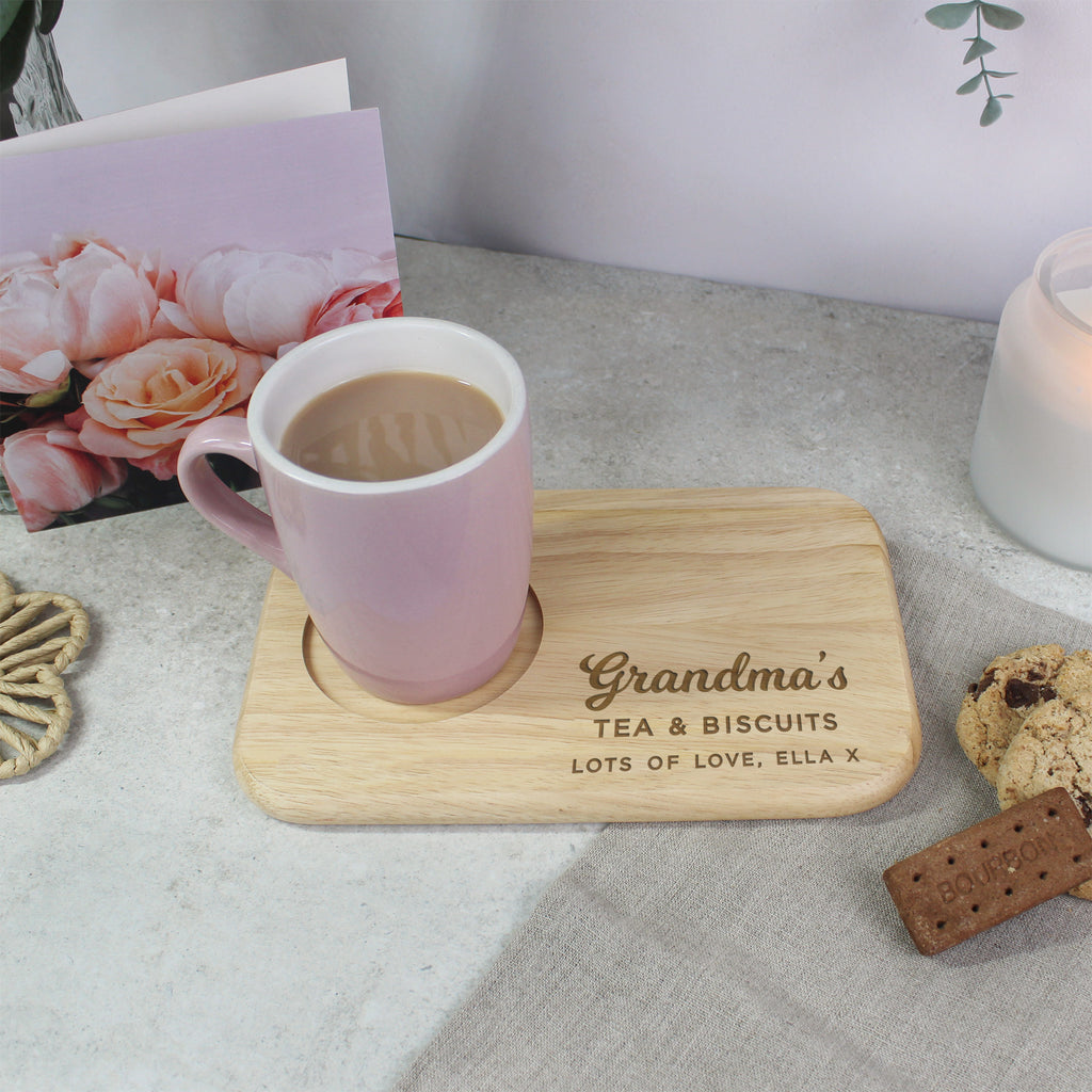 Pink mug with wooden coaster and cookies on a surface