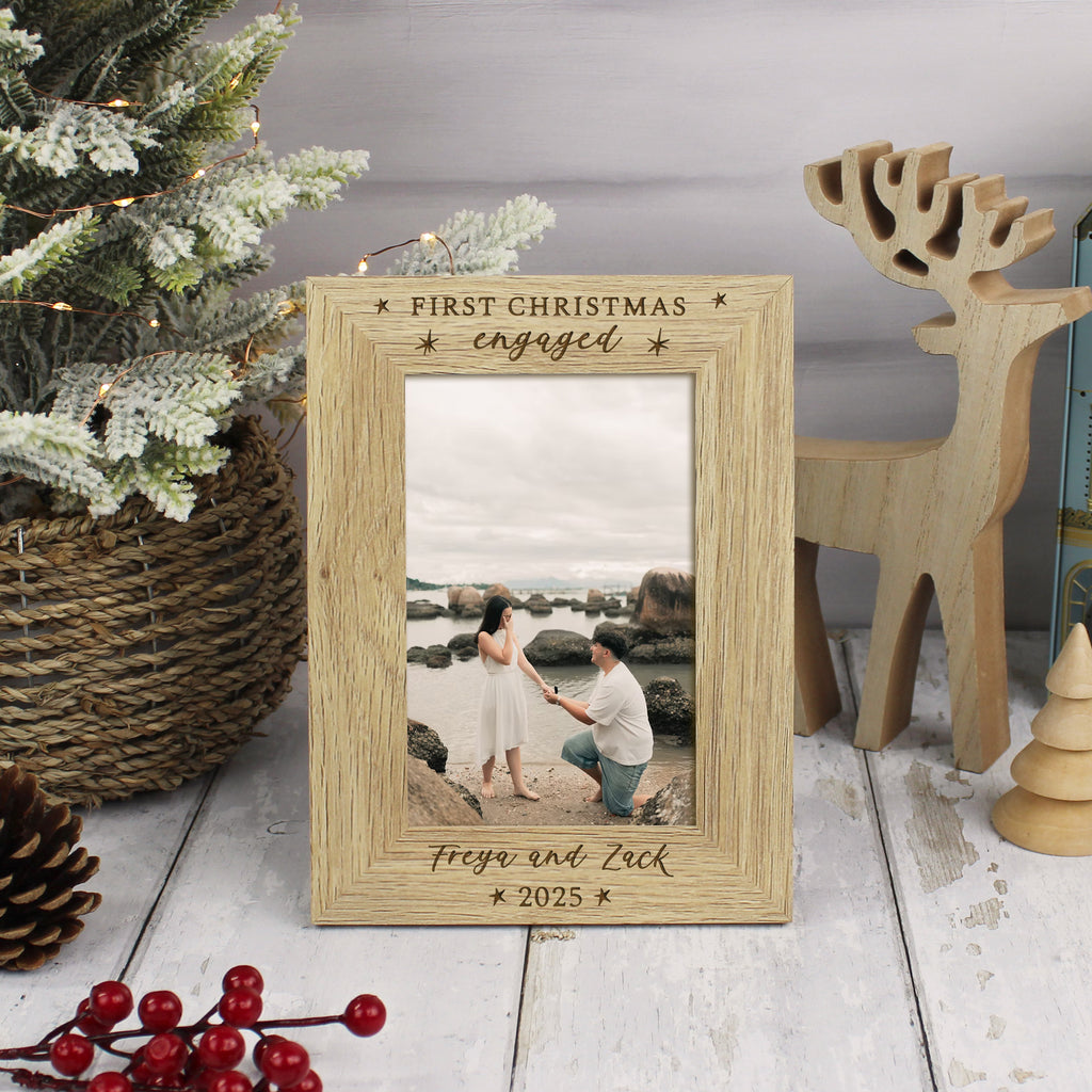 Wooden photo frame with 'First Christmas engaged' text, placed on a surface with decorative items.