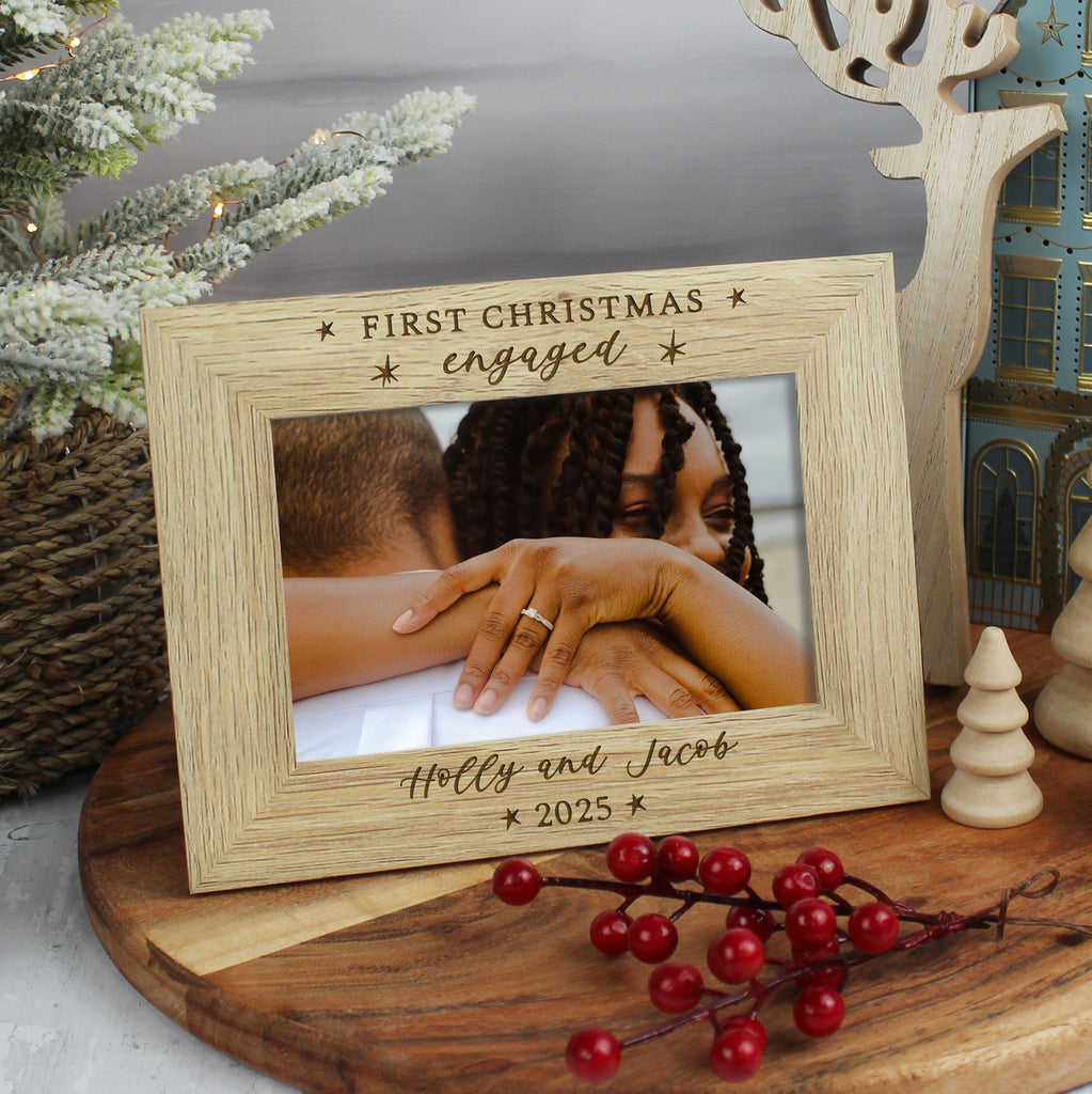 Wooden photo frame with engraved text and a couple's hands, surrounded by festive decorations.