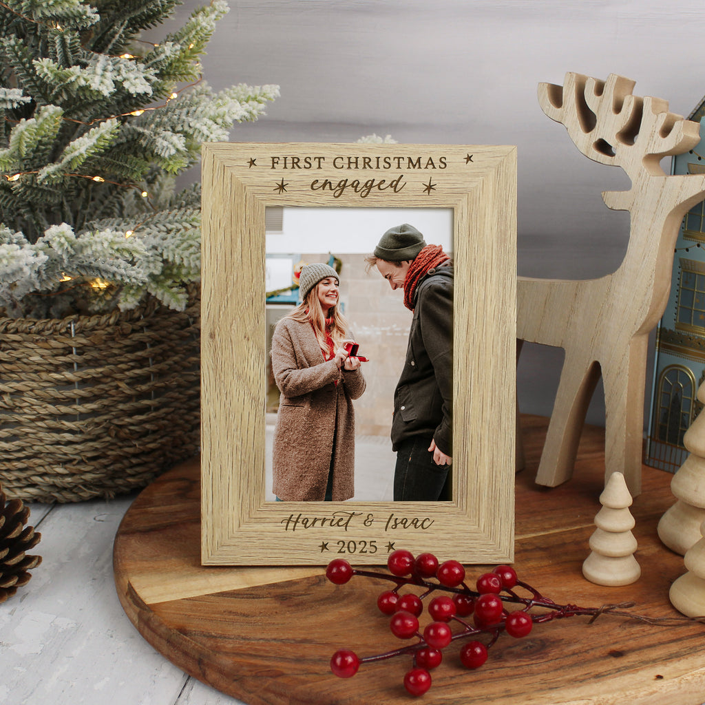 Wooden photo frame with a Christmas-themed message, placed on a wooden surface with festive decorations.