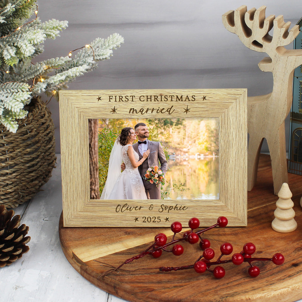 Wooden photo frame with a wedding picture and 'First Christmas married' text, surrounded by festive decorations.