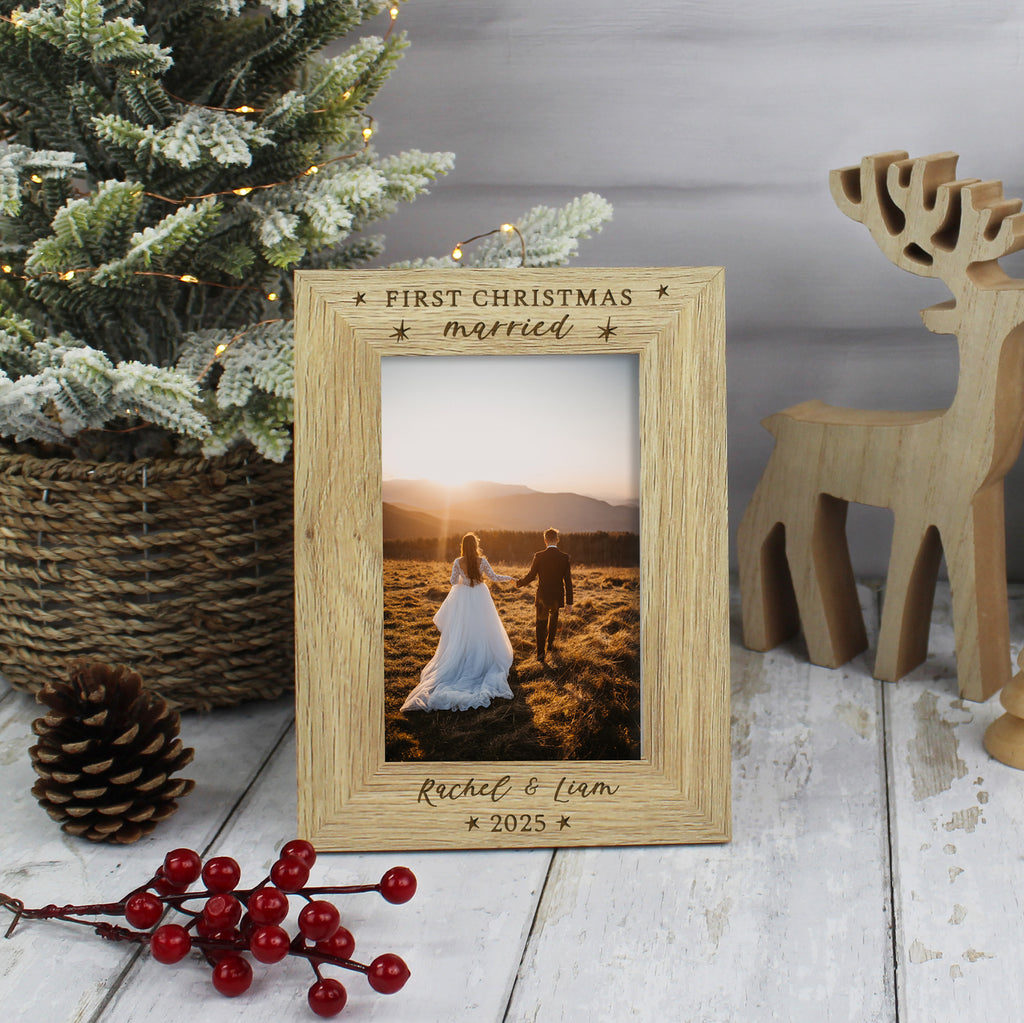 Wooden photo frame with a couple's picture, engraved 'First Christmas married', on a festive background with a Christmas tree and reindeer.