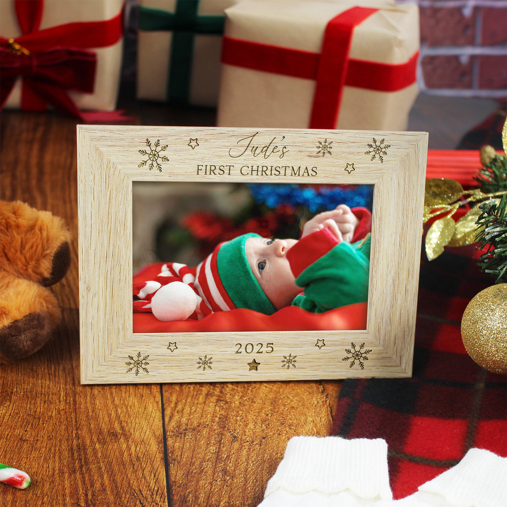 Wooden photo frame with a baby's first Christmas picture, surrounded by festive decorations and gifts.
