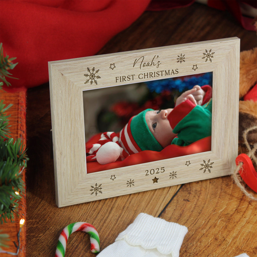 Wooden photo frame with a Christmas-themed engraving of a baby's first Christmas, surrounded by festive decorations.