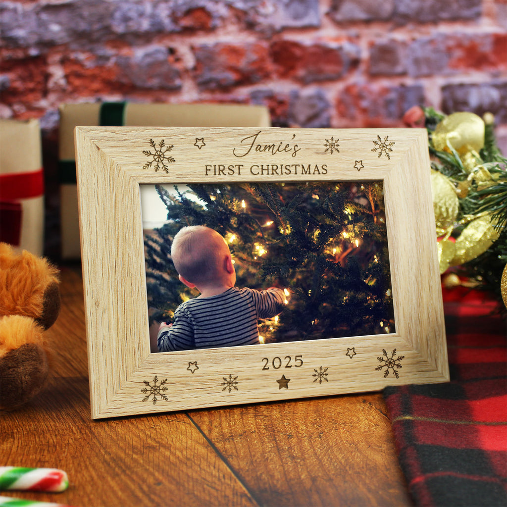 Wooden photo frame with a picture of a baby under a Christmas tree, placed on a wooden surface with a festive background.