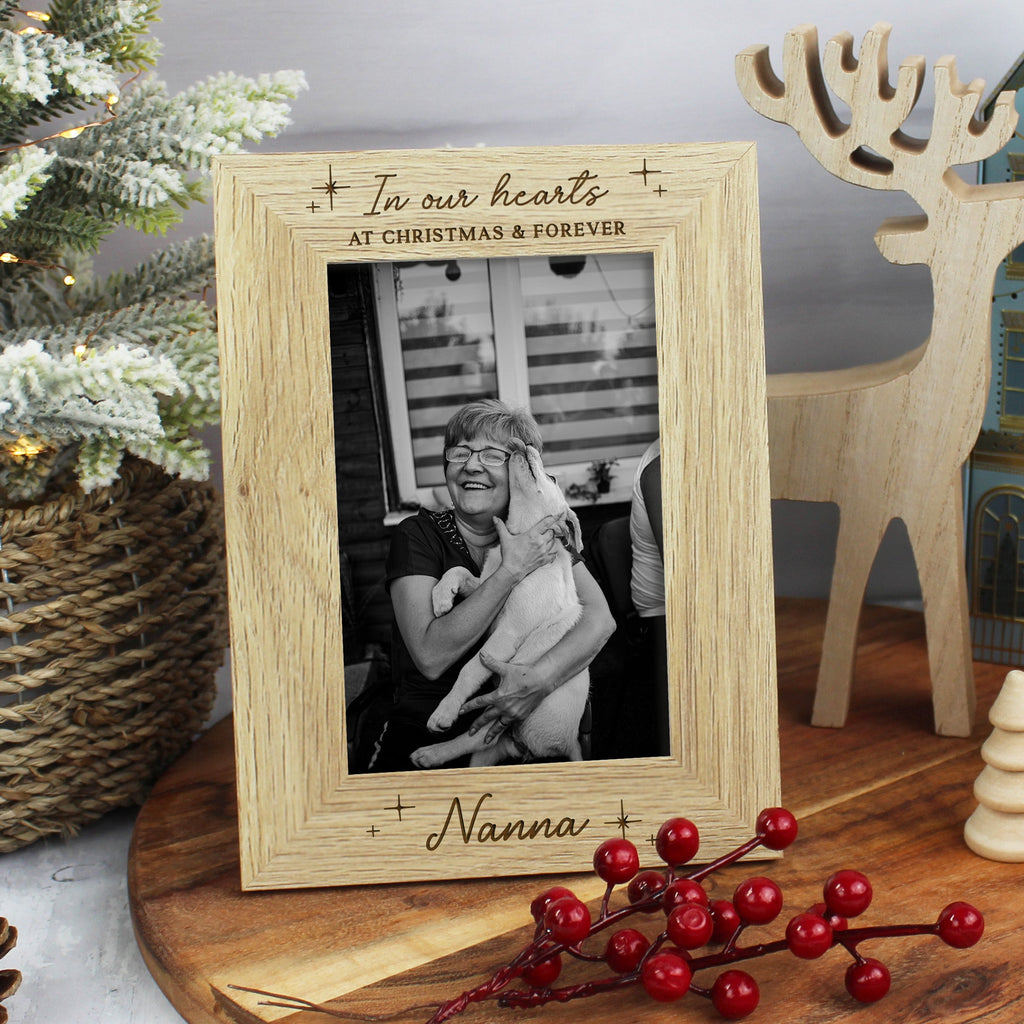 Wooden photo frame with engraved text, placed on a wooden surface with Christmas decorations.