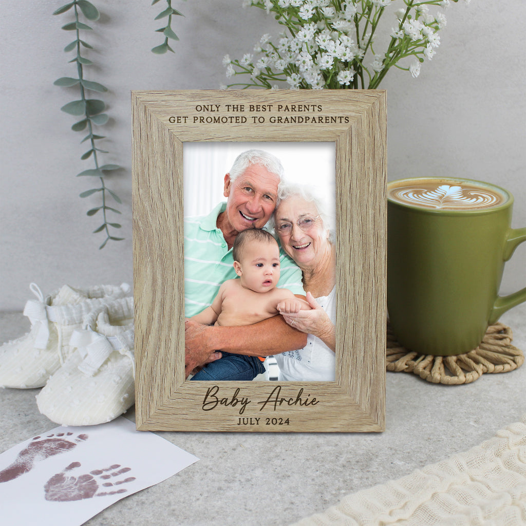 Wooden photo frame with engraved text, placed on a surface with a cup of coffee and baby items.
