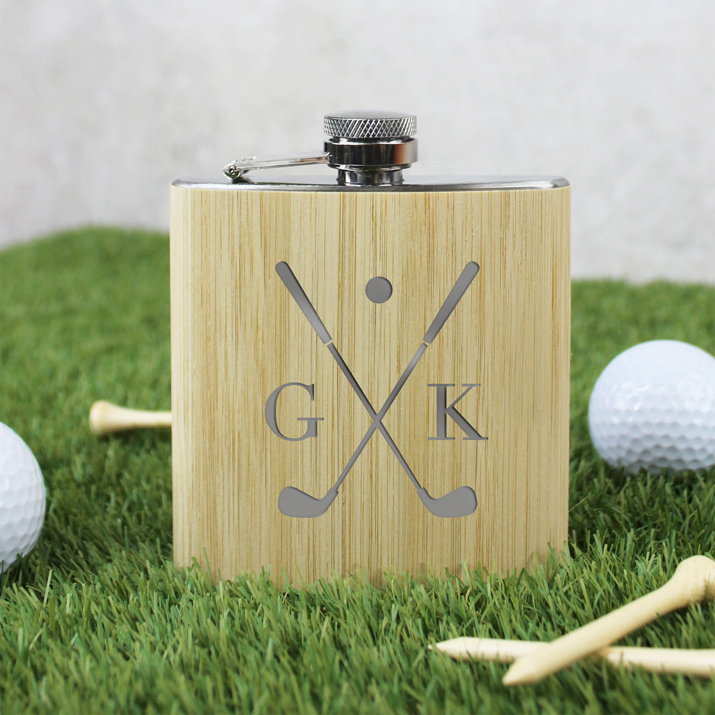 Wooden flask with golf design and initials on grass with golf balls and tees