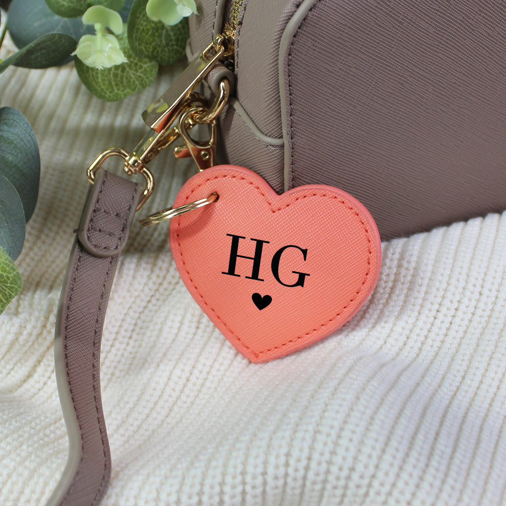 Heart-shaped keychain with 'HG' initials attached to a bag.