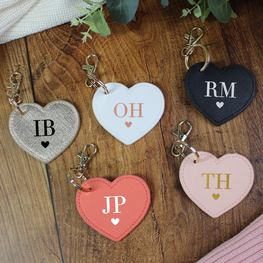 Heart-shaped keychains with initials on a wooden surface