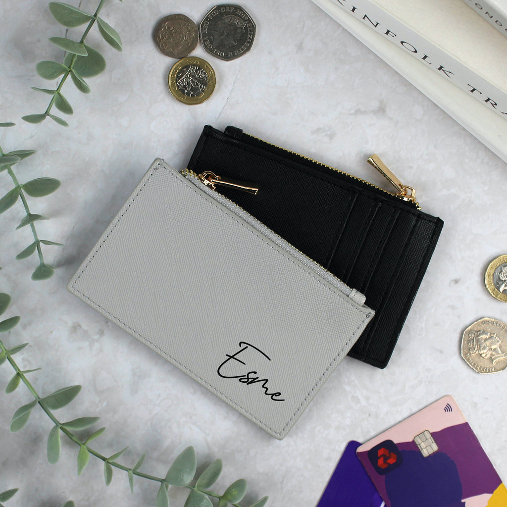 Two wallets, one gray and one black, on a marble surface with coins and cards around.
