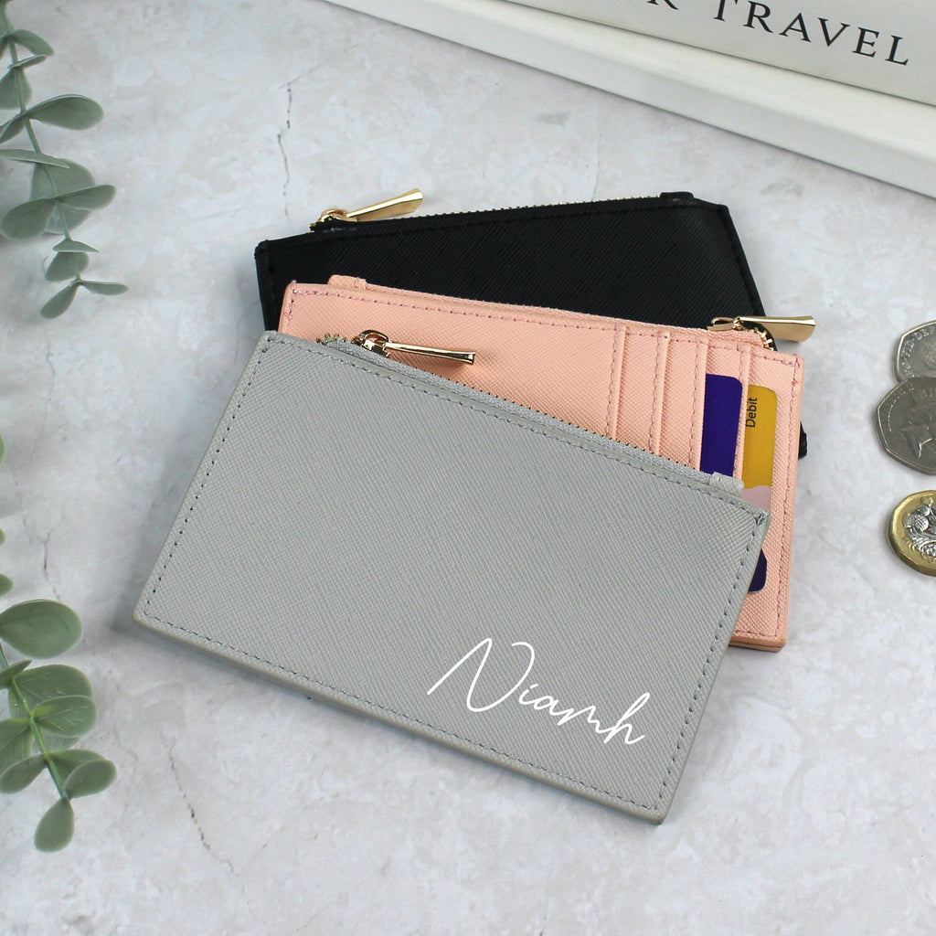 Gray wallet with 'Nianh' branding on a light surface with coins and a plant.