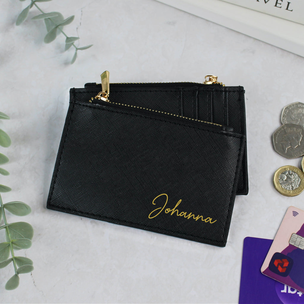 Black wallet with 'Johanna' engraving on a light gray surface with coins and cards.