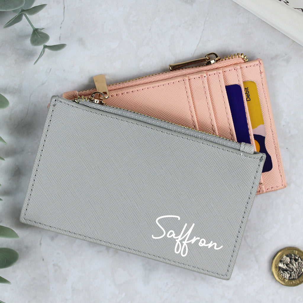 Two wallets, one gray and one pink, with 'Saffron' branding on a light background.
