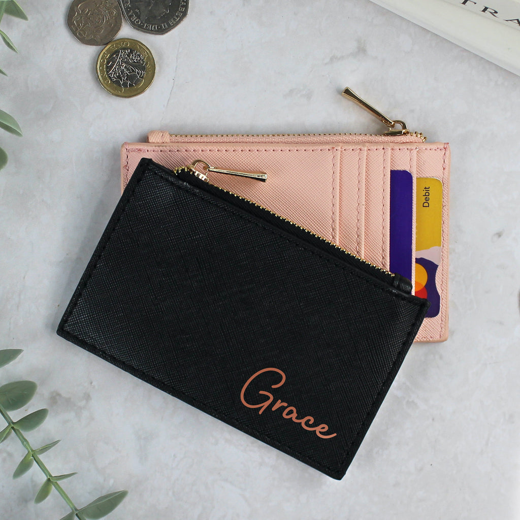 Black wallet with 'Grace' embroidery on a marble surface with pink wallet and coins.