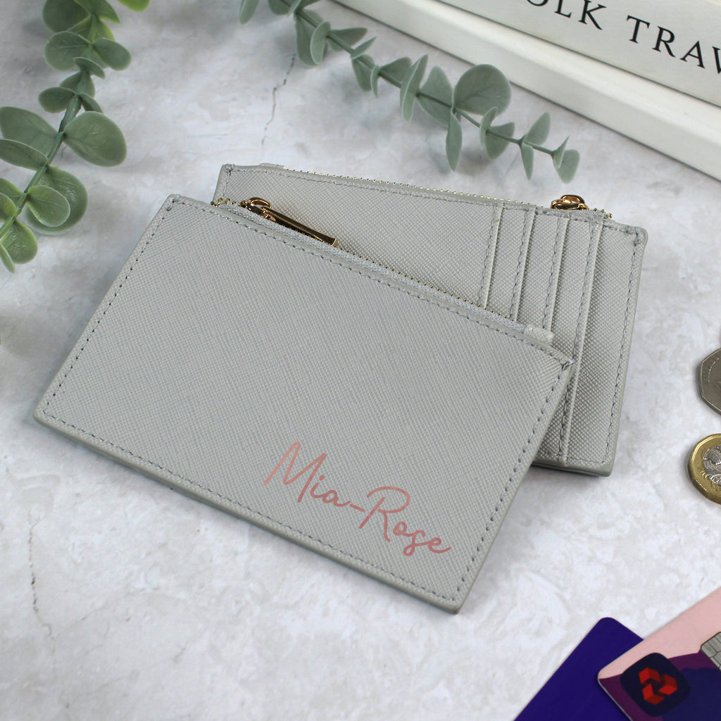 Light gray wallet with 'Mia Rose' embroidery on a white surface with greenery.