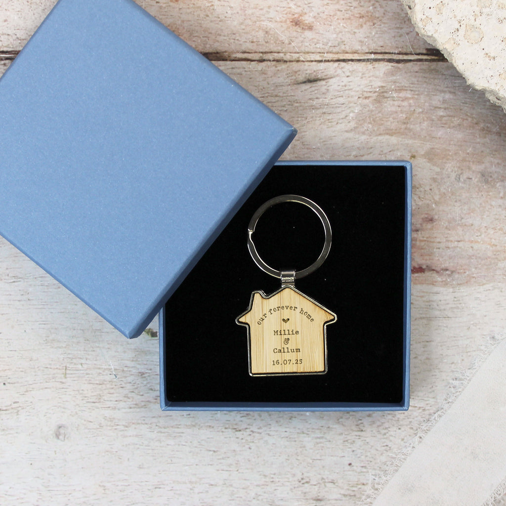 House-shaped keychain in a blue box on a wooden surface