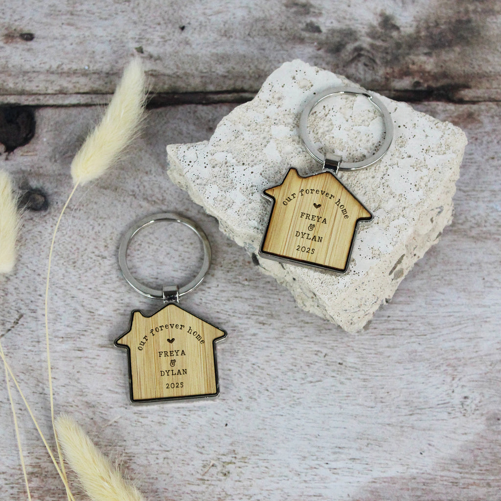 Two wooden keychains shaped like houses on a textured surface with decorative elements.