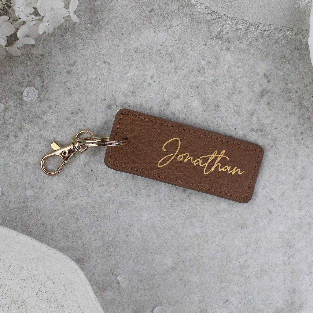 Brown leather keychain with 'Jonathan' engraving on a gray surface