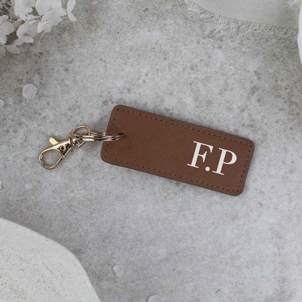 Brown leather keychain with 'F.P.' initials on a gray surface