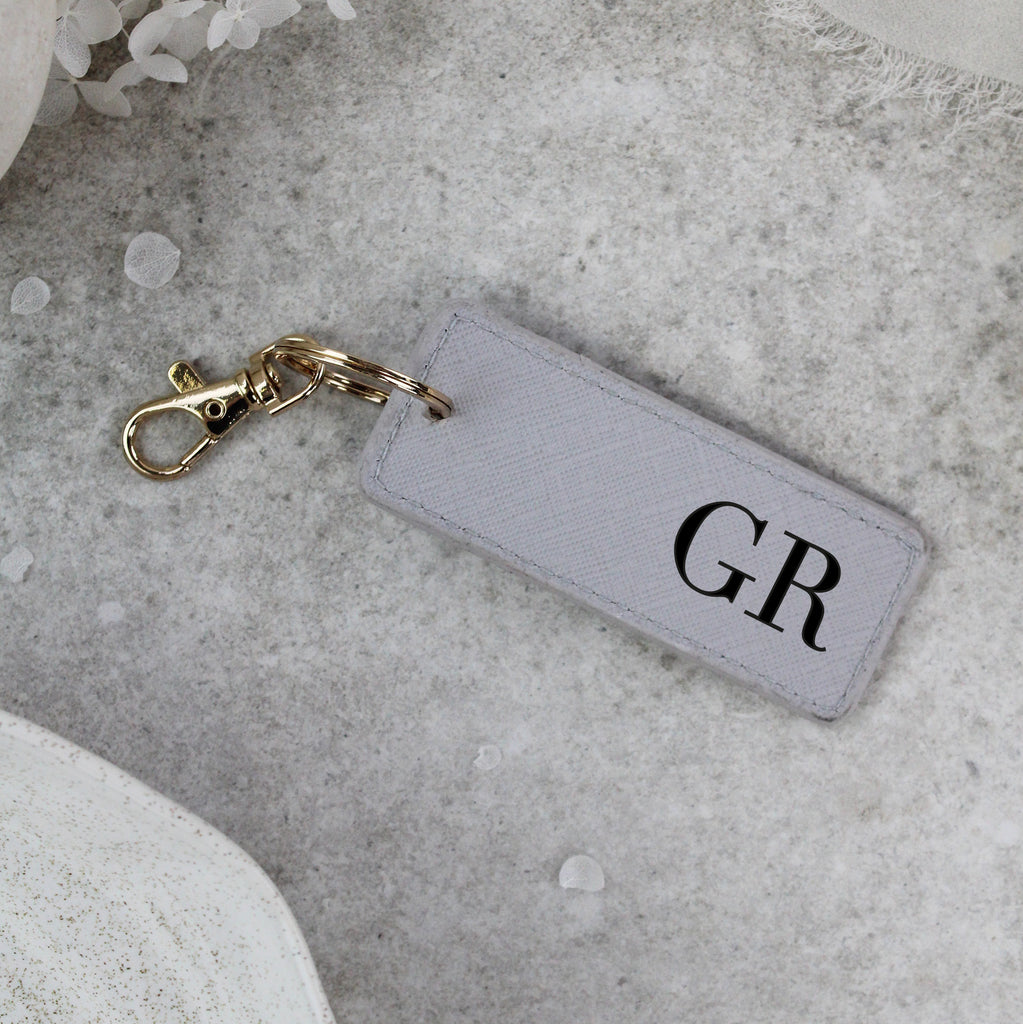 Keychain with 'GR' initials on a gray surface