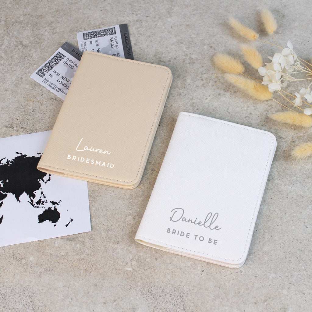 Two personalized passport holders on a concrete surface with travel-related items.