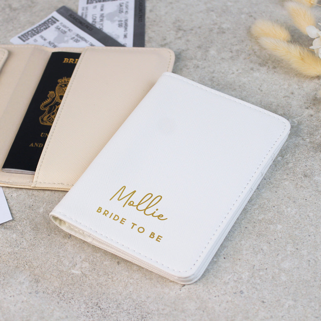 White notebook with 'Mallie Bride To Be' text on a concrete surface with passports and a card.