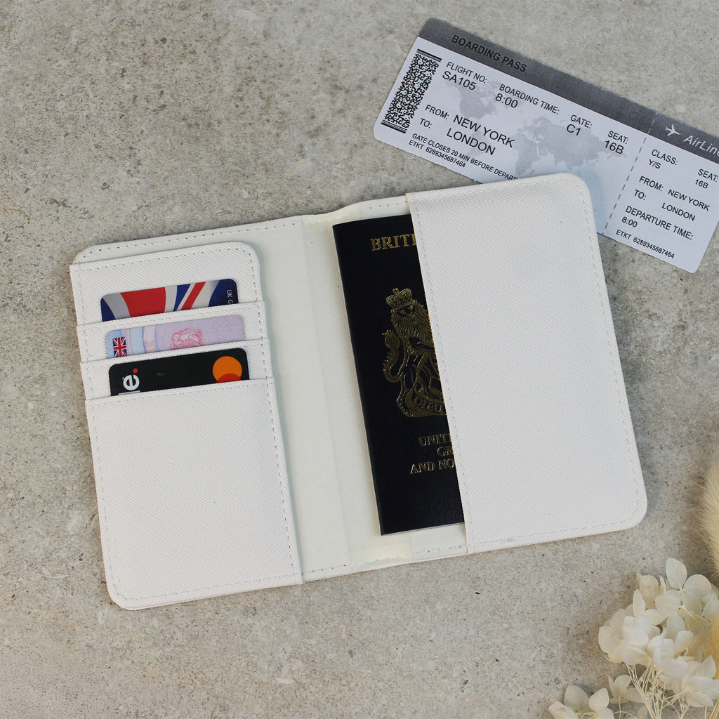 White travel wallet with passport, cards, and boarding pass on a textured surface.