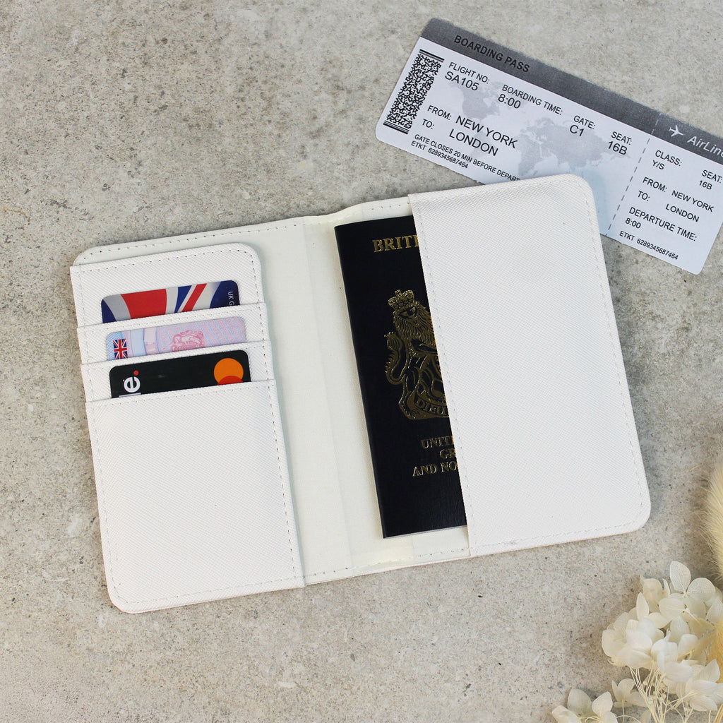 White passport holder with a British passport, cards, and boarding pass on a light gray surface.