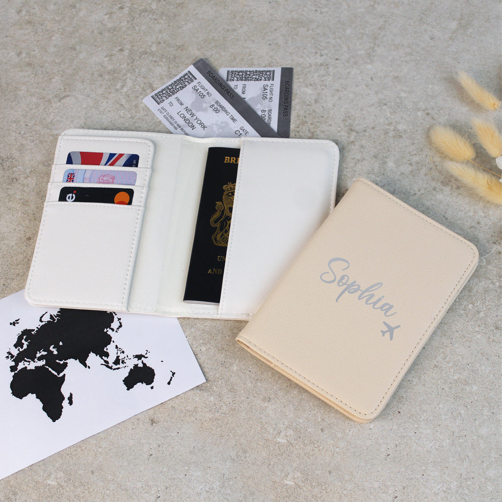 White travel wallet with passport, cards, and tickets on a concrete surface with 'Sophia' notebook.